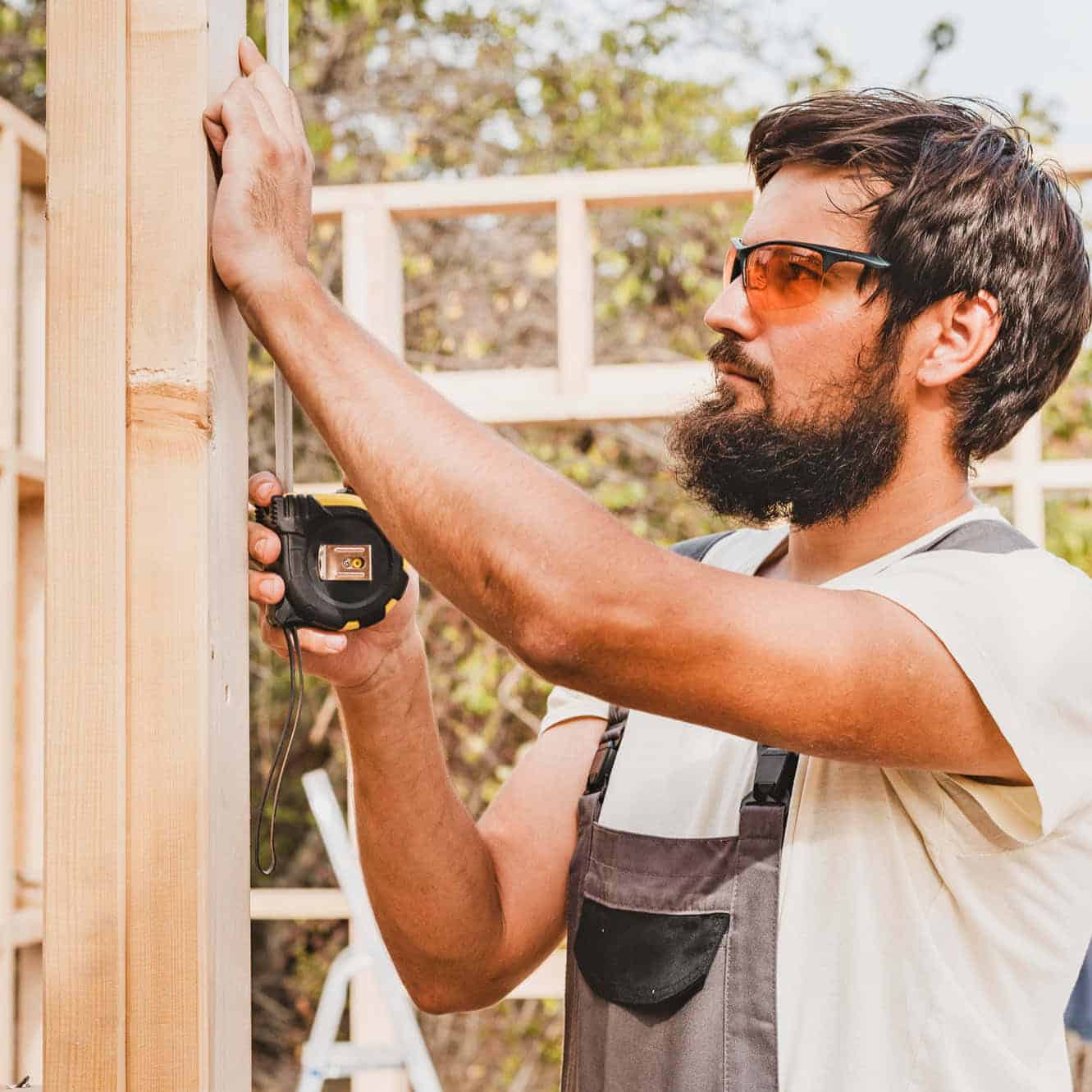 Hombre midiendo con una cinta métrica en construcción.