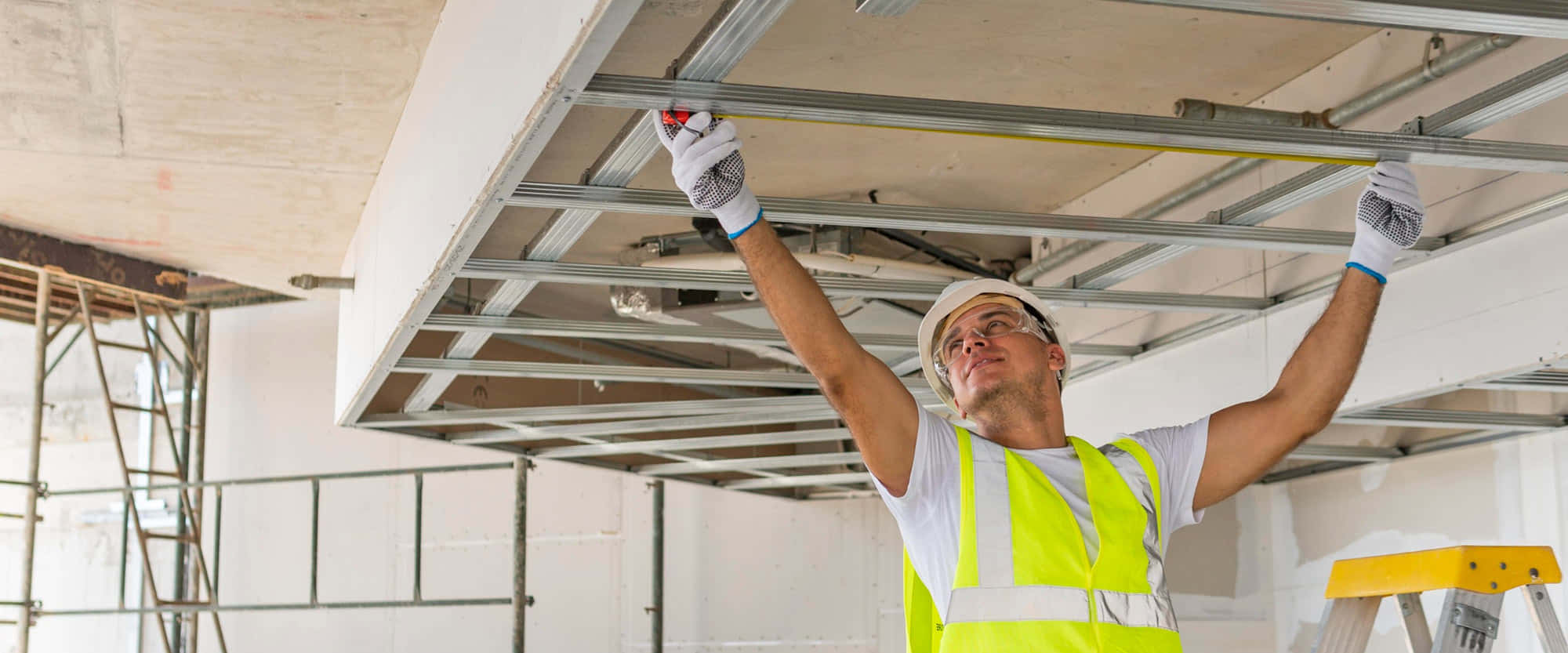 Trabajador construyendo estructura de techos interiores.